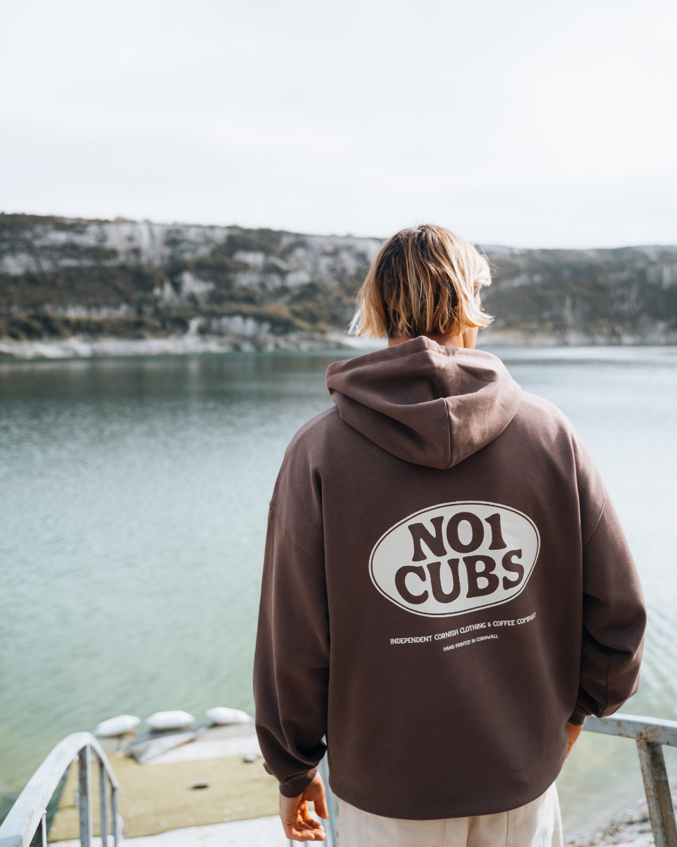 Person wearing a brown hoodie with &