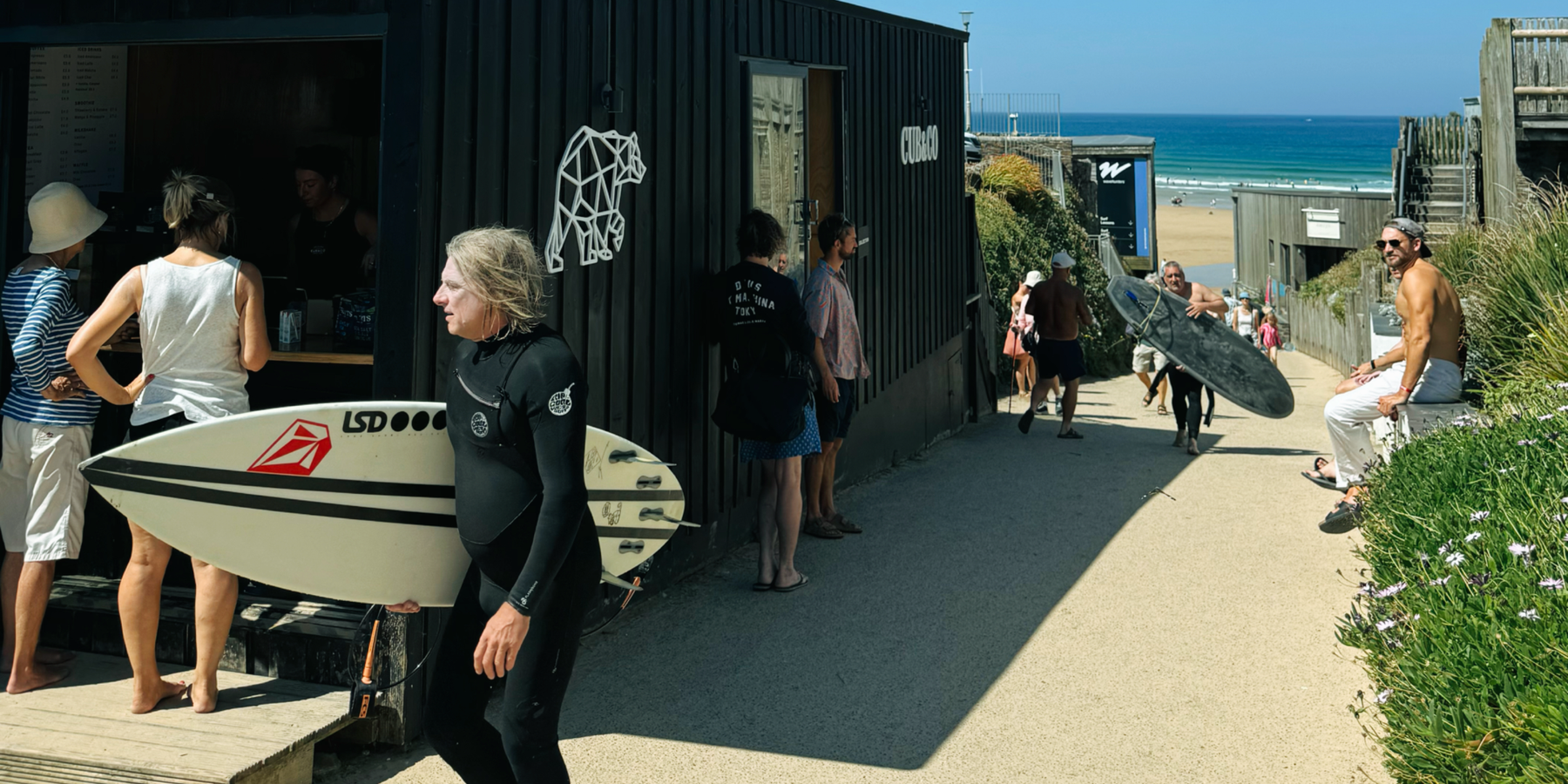 Surfers passing the Cub&Co coffee cabin at Watergate Bay